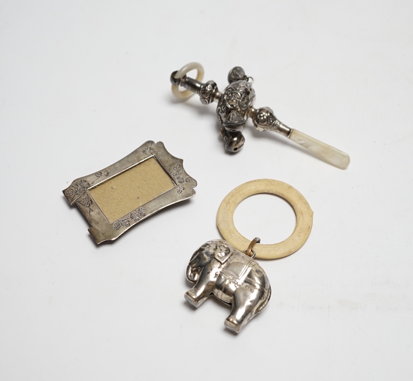 An Edwardian silver and mother of pearl child's rattle, 11cm, together with a miniature white metal photograph frame and a plated child's rattle.